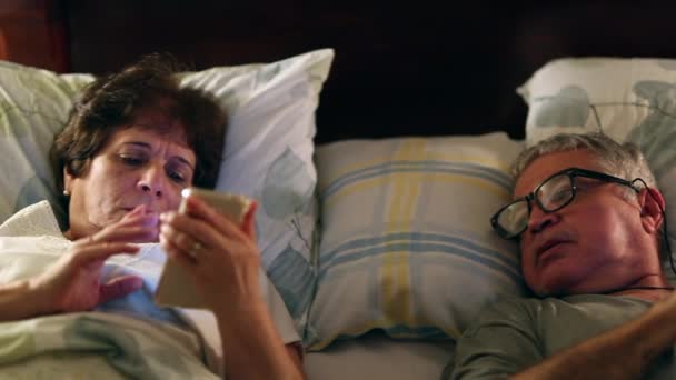 Ηλικιωμένο Ζευγάρι Ξαπλωμένο Στο Κρεβάτι Κοιτάζοντας Οθόνη Smartphone — Αρχείο Βίντεο