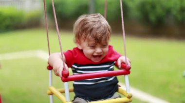 Joyful baby at playground swing