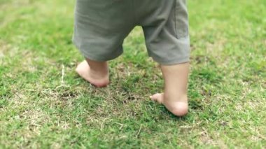Baby feet walking barefoot on grass outdoors