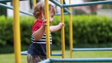 Joyful cute baby toddler infant entering playground monkey bar
