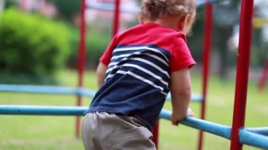 Active child baby inside metal monkey bar at playground