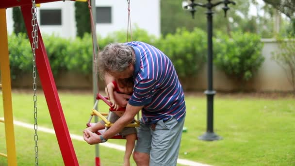 Grandfather Helping Grandson Playground Swing Grandparent Putitng Infant Baby Swing — Stock videók