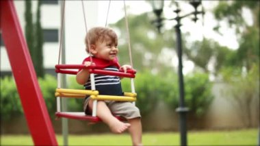Happy baby at playground swing in slow-motion