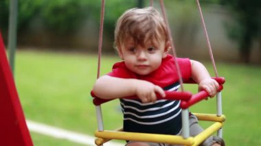 Adorable cute toddler baby infant at playground swing