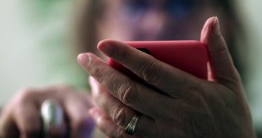 Akıllı telefon cihazı tutan yaşlı bir kadın, cep telefonu ekranına bakan otantik bir büyükanne.