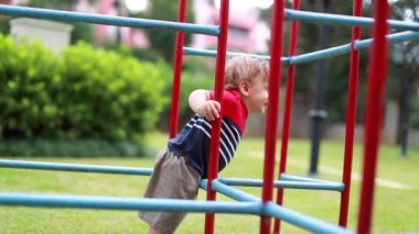Baby toddler boy playing with metal monkey bars