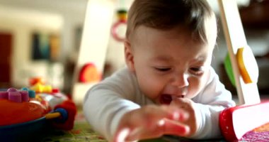 Upset baby lying on floor looking at camera, portrait infant face