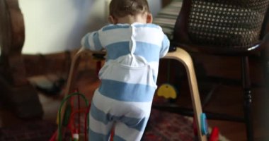 İçeride oyuncaklarla oynayan samimi bir bebek. Çocuk oyun odasında yerde oturuyor.