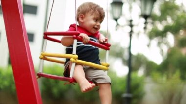 Grandfather pushing baby grandson at swing. Infant and grandpa generation bonding at playground
