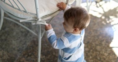 Sevimli bebek, iskemleye yaslanarak ayakta durmayı öğreniyor.