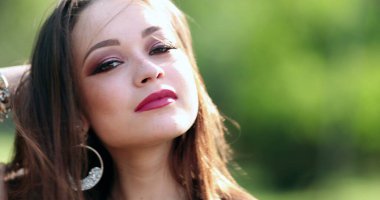 Yirmili yaşlardaki çekici İspanyol kadın dışarıda poz verirken kameraya bakıyor.