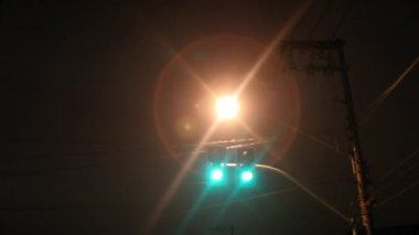 Passenger perspective in motion at night of lamp post light passing by and green light