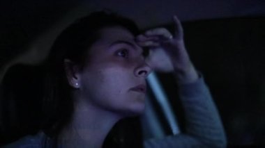 Woman driving at night with concerned anxious look on her face