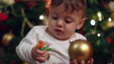 Baby looking at christmas tree during holidays. Infant toddler next to blinking lights