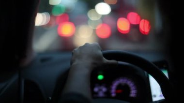 POR of driver holding steering wheel driving at night in city, stuck in traffic