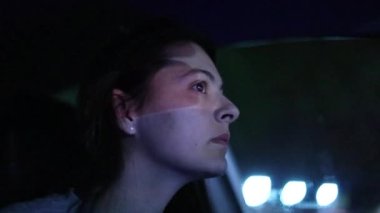 Woman face driving at night with city light motion in background. Female driver in urban city slow-motion