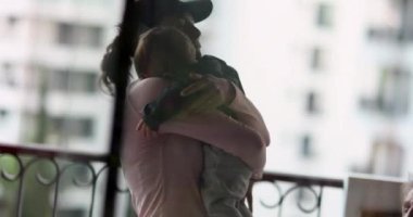 Anne bebeğe sarılıyor. Anne kucağında küçük bir çocuk.