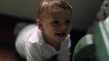 Happy smiling baby on home floor looking up with bright smile