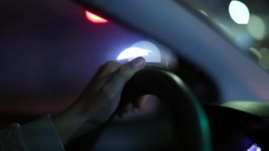 Hand holding steering wheel driving at night making a left turn