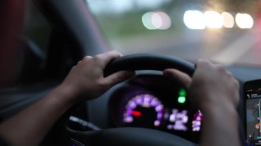 Driver hands holding steering wheel driving in city. Person POV point of view