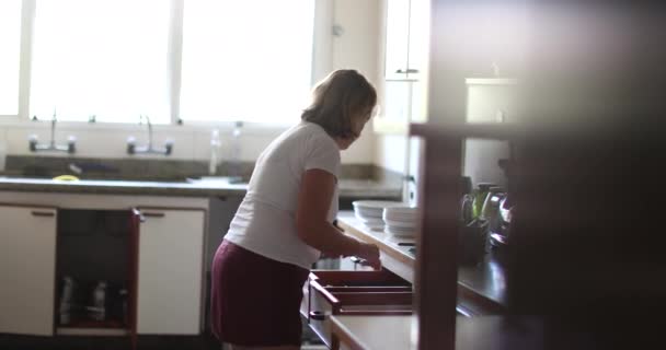 Starsza Kobieta Kuchni Sprząta Porządkuje Naczynia Szufladach Niemowlę Czołga Się — Wideo stockowe