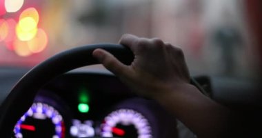 Commuter hand closeup driving at night holding car steering wheel