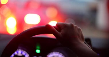 Commuter waiting in traffic jam. Close-up hand holding steering wheel stuck in traffic POV