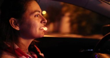 Woman driving at night in city, female driver