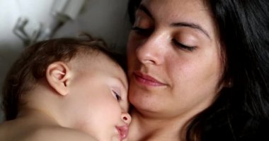 Casual candid mother and baby together napping. Mom and infant asleep