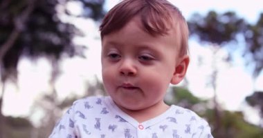 Portrait of baby outside in park nature. Beautiful one year old toddler child smiling to camera