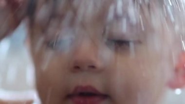 Showering baby close-up face in slow-motion. Toddler infant boy shower water