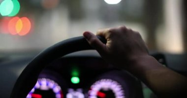 Driving in city in evening, Driver hands POV