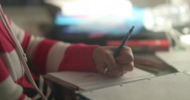 Concentrated woman studying taking notes at night. Candid casual person working from home, scratching face thinking