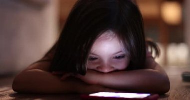 Cute little girl watching media on cellphone device at night