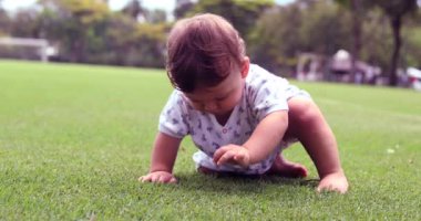 Toddler boy sitting on grass outside in nature park