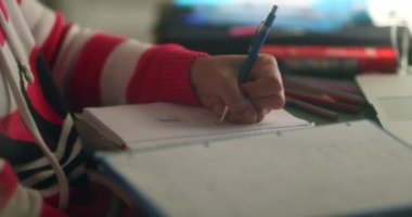 Woman taking notes studying at night, candid person scratching face while in concentration