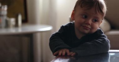 Cute baby holding to table, infant boy learning to stand leaning on table