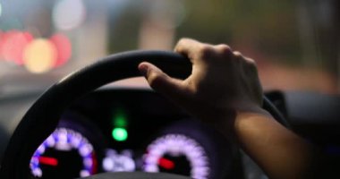 Female driver holding car steering wheel driving at night in city