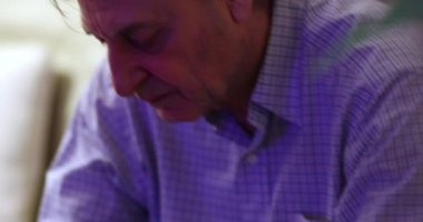 Candid man peeling apple in pieces. Older man eating healthy snack at night