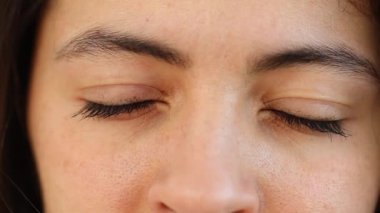Woman closing eyes in meditation and contemplation, macro close-up female casual eyes