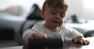 One year old baby playing with object scrubbing table surface