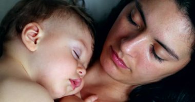 Mother and baby sleeping napping together. Casual mom and infant child asleep nap