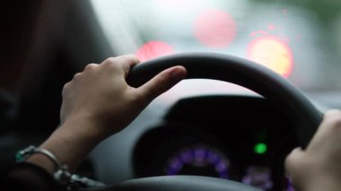 Driver holding steering wheel stopped in traffic waiting, close-up woman hands