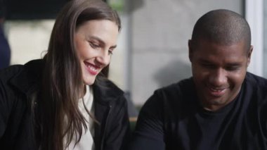 Kafede oturan çeşitli erkek ve kadınlar. Kafede siyah bir adamla beyaz bir kız.