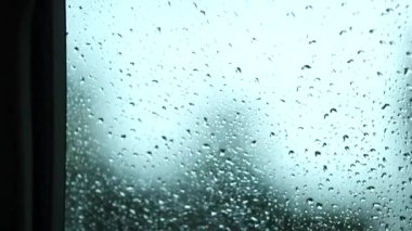 Raindrops at car window during rainy day in motion