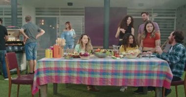 Arka bahçedeki barbekü partisinde aile toplantısı. Barbekü masası. Çeşitli arkadaşlar kutlama için bir araya geldi. Yaz tatili