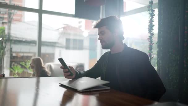 Mladý Muž Dívá Mobil Kavárně Před Laptopem Osoba Procházení Internetu — Stock video