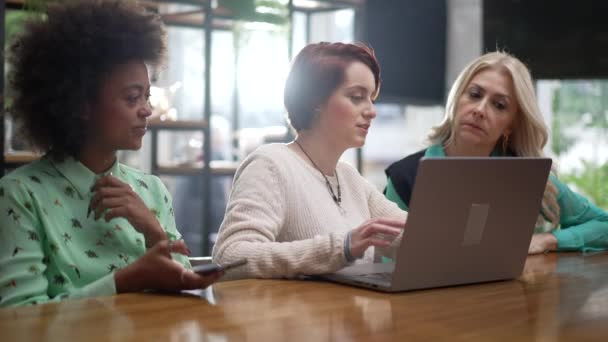 コーヒーショップに座ってノートパソコンの前に3人の多様な女性 若い女性執行役員コーチング従業員 — ストック動画