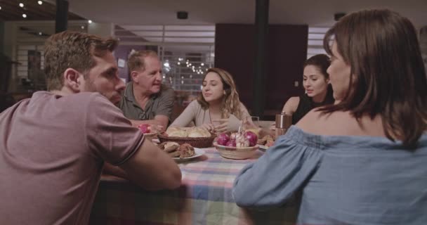 家族や友人が家の裏庭で夜に家の外に集まった 夕食のテーブルに座って会話する人々のグループ — ストック動画