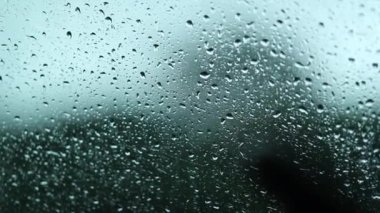 Raindrops at car window during rainy day in motion